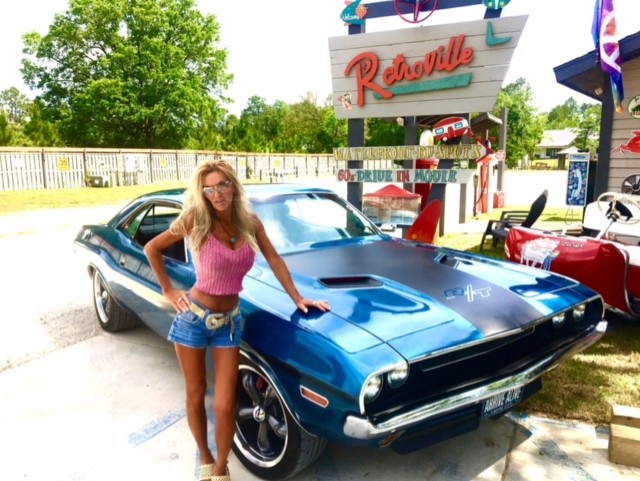 Woman standing next to blue Dodge Challenger