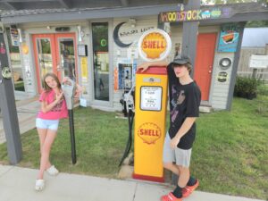 Young boy and girl next to retro Shell gas pump and parking meter