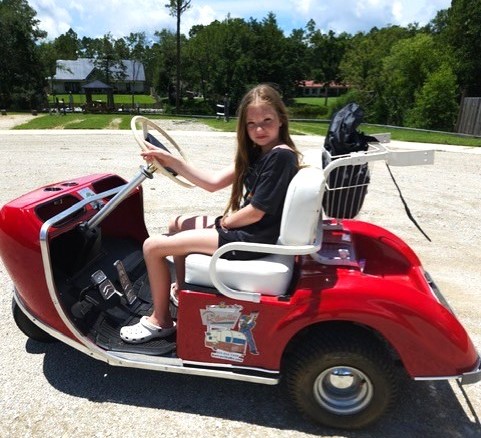 Young girl sitting in retro golf cart