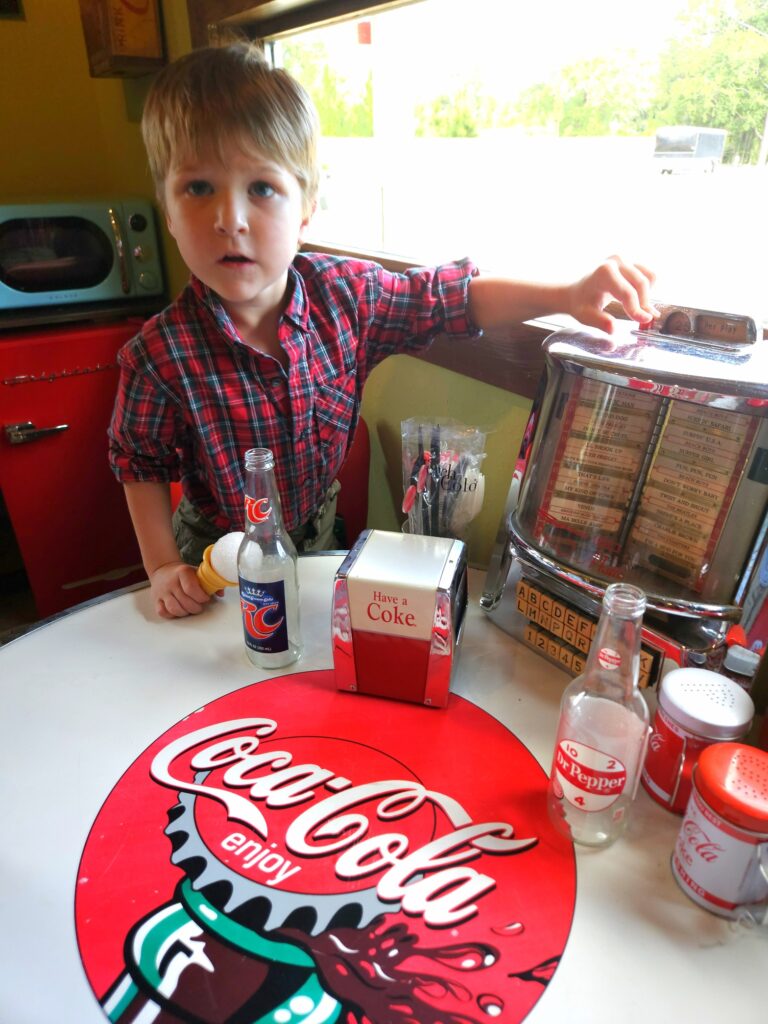 Young boy sitting at retro diner table and table top juke box