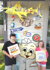 Young boy and girl in front of retro logos holding Beatles album covers